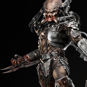 May include: A detailed statue of a Predator alien, featuring intricate armor and weaponry. The figure has a textured, brown and tan skin tone, with sharp claws and a menacing expression. The background is black, highlighting the figure's details.