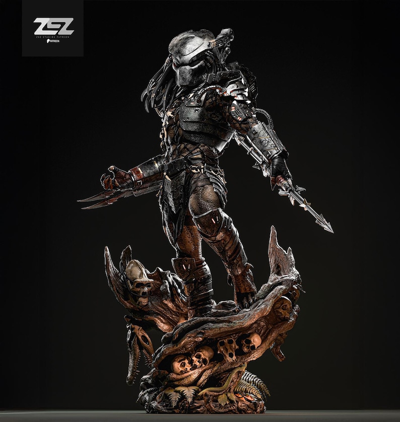 May include: A detailed statue of a Predator warrior, standing on a base adorned with skulls and organic textures. The figure is clad in dark armor, holding bladed weapons, and features a masked face. The statue is a collectible item.