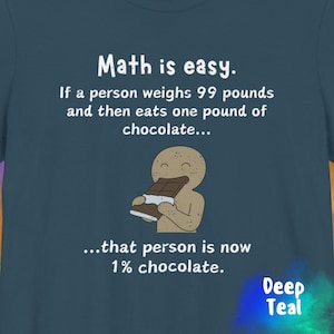 May include: Deep teal t-shirt with the text "Math is easy." and a humorous illustration of a person eating chocolate. The text continues with a math problem and the answer. The shirt is a solid color.