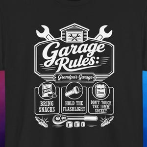 May include: Black t-shirt with a white graphic. The design includes the words "Garage Rules" and three illustrated boxes with text: "Bring Snacks", "Hold the Flashlight", and "Don't Touch the 10MM Socket".
