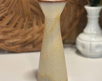 May include: A beige ceramic vase with a speckled texture and a flared top. The vase has a brown rim and a conical shape, standing approximately 7 inches tall. The vase is a decorative item.