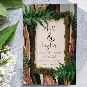 Könnte beinhalten: Hochzeitseinladung im rustikalen Stil. Die Einladung zeigt einen Hintergrund aus Holz und Moos mit Farnen und dem Text "Matt & Taylor" mit Datum und Uhrzeit der Hochzeit.