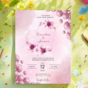 Può includere: Un invito di nozze rosa con un design floreale e una cornice a forma di cuore geometrica. L'invito recita "Caroline & James" e include la data e l'ora della cerimonia di nozze. L'invito è decorato con palloncini rosa.