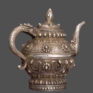 May include: A silver teapot with a dragon-shaped handle and intricate floral designs. The teapot has a round body and a domed lid with a finial.