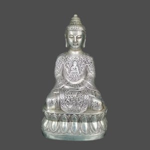 Puede incluir: Estatua de Buda plateada en posición sentada, con intrincados patrones grabados en la túnica y la base. La estatua tiene una expresión serena y está sobre un fondo gris. La base tiene forma de flor de loto.