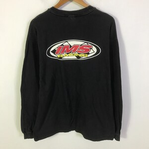 Könnte beinhalten: Ein schwarzes Langarm-T-Shirt mit einer Grafik auf der Rückseite. Die Grafik ist oval geformt mit einem karierten Hintergrund und enthält den roten Schriftzug IMS sowie den gelben Schriftzug RACING. Das Shirt hat einen Rundhalsausschnitt.