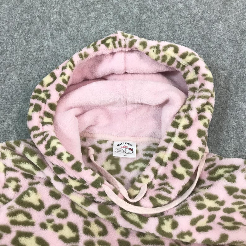 Puede incluir: Sudadera con capucha rosa y verde oliva con estampado de leopardo, con cord&oacute;n y interior rosa. La sudadera con capucha tiene una etiqueta de Hello Kitty.