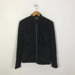 May include: Black jacket with a full-length zipper and a stand-up collar. The jacket has a quilted front panel and long sleeves. The jacket is hanging on a wooden hanger against a white background.