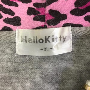 May include: Close-up of a gray hoodie with a pink and black leopard print hood lining. The label reads "Hello Kitty" in white text.