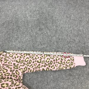 Puede incluir: Tejido polar rosa y beige con estampado de leopardo. Se mide la tela con una cinta m&eacute;trica. La manga es rosa con un lazo rosa. La tela es suave y afelpada.