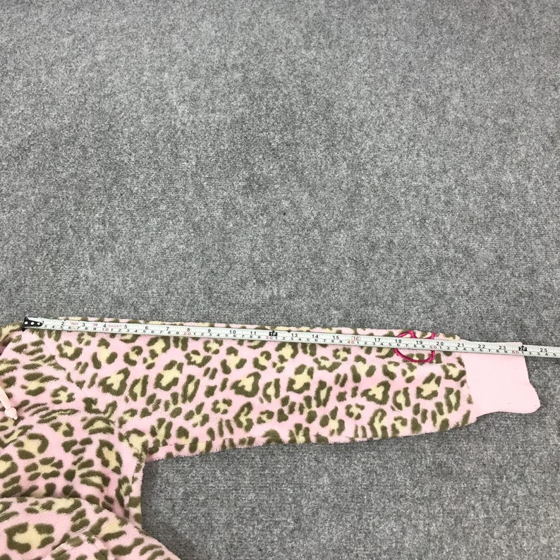 Puede incluir: Tejido polar rosa y beige con estampado de leopardo. Se mide la tela con una cinta m&eacute;trica. La manga es rosa con un lazo rosa. La tela es suave y afelpada.