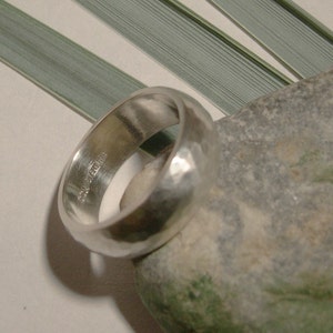 May include: A silver band ring with a hammered finish. The ring is marked "925 Sterling".