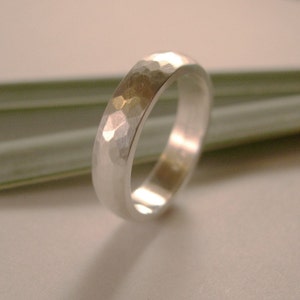May include: A silver hammered wedding band with a rounded profile.