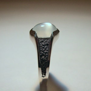 Peut inclure: Une bague en argent avec une pierre de lune blanche sertie dans une bande texturée.