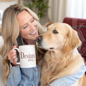 Könnte beinhalten: Eine Frau hält eine weiße Kaffeetasse mit dem Text "Design here" in braunen Buchstaben. Sie lächelt und schaut auf einen Golden Retriever, der auf ihrem Schoß sitzt.