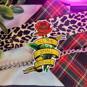May include: A sticker with a red rose and a yellow banner that reads "All the small things".