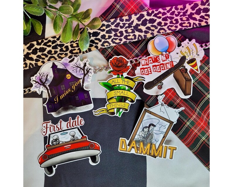 May include: A set of nine stickers featuring various designs, including a haunted house, a car with skeletons, a rose with the text "All the small things", a skateboard with the text "What's my age again?", and a picture frame with the text "Dammit".