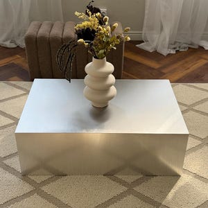 Minimalistiskt sidobord i aluminium. Modernt accentbord i metall. Moderna designmöbler. Vasställ. Vardagsrumsinredning