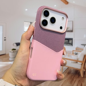 Op de afbeelding: Een roze en mauve telefoonhoesje met een bovenkant van textuurgaas en een gladde, effen roze onderkant. De hoes heeft een goudkleurig camerakader en de letters "QZ" zijn op de onderkant gedrukt.