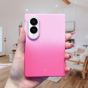 May include: A rectangular smartphone case featuring a vibrant pink ombre gradient that transitions from a lighter shade at the top to a deeper pink at the bottom. The case includes a vertical dual-camera cutout with silver trim and the letters QZ.