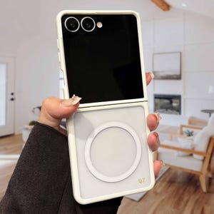 Könnte beinhalten: Eine weiße Handyhülle mit quadratischem Design und kreisförmigem Akzent. Die Hülle hat einen schwarzen Bildschirm und ein Kameramodul mit zwei Linsen. Die Buchstaben "QZ" sind unten rechts sichtbar.