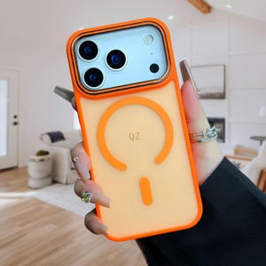 May include: Bright orange and clear phone case featuring a circular design and the letters "QZ". The case has an orange border and a clear back. The phone case is designed to protect the phone's camera.