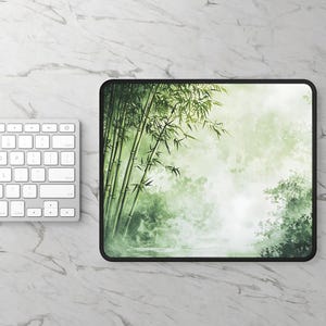 Stitched mousepad with a green bamboo forest design, placed on a light wood desk with a computer, tablet, and blue hydrangea flowers in a gray pot.