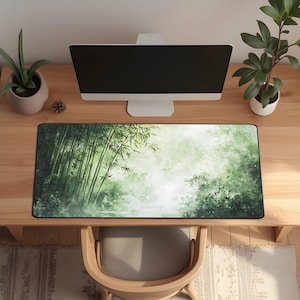 Desk mat with a green bamboo forest design, placed on a light wood desk with a computer, tablet, and blue hydrangea flowers in a gray pot.