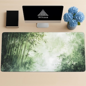 Desk mat with a green bamboo forest design, placed on a light wood desk with a computer, tablet, and blue hydrangea flowers in a gray pot.