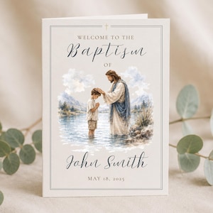 May include: A rectangular white baptism programme card featuring a watercolour illustration of a figure blessing a child in a lake. The text reads: WELCOME TO THE BAPTISM OF John Smith MAY 18, 2025. The card has a thin border and a small cross icon at the top.