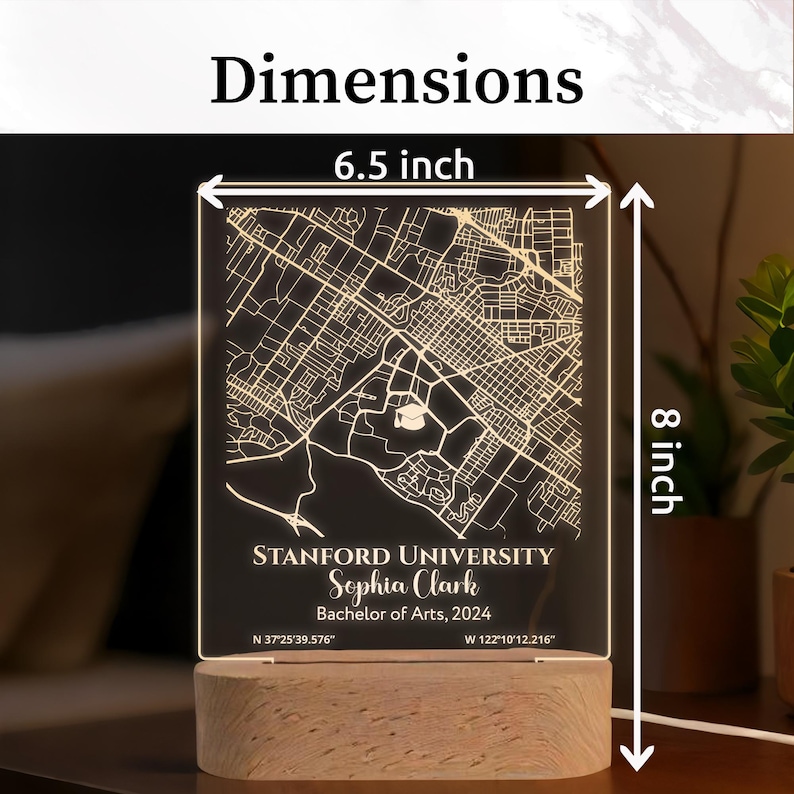 May include: A personalized LED map of Stanford University, 6.5 x 8 inches, with the name Sophia Clark and Bachelor of Arts degree details. The map is etched on a clear acrylic panel, illuminated by a wooden base. The dimensions are indicated on the image.
