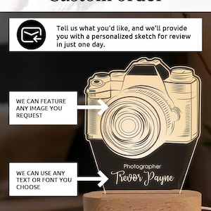 May include: A custom-made light-up camera-shaped sign with the name "Trevor Payne" and the word "Photographer" engraved on it. The sign is mounted on a wooden base. The text "Custom order" and other text are also visible.