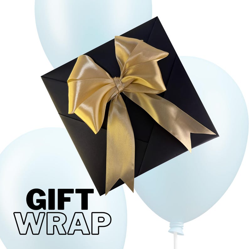 May include: A black gift box with a gold satin bow, set against a backdrop of light blue balloons. The words "GIFT WRAP" are printed in bold, white letters on a balloon. The bow adds a touch of elegance to the presentation.