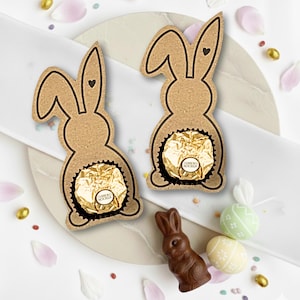 Könnte beinhalten: Eine weiße Keramik-Tasse mit schwarzem Henkel und dem Text "But First, Coffee" in schwarzer, handschriftlicher Schrift. Die Tasse steht auf einer weißen Oberfläche.