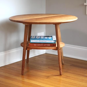 Mesa auxiliar circular hecha a mano con estante inferior para guardar libros