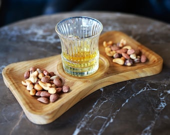 May include: A wooden serving tray with three compartments, one for a glass of whisky and two for mixed nuts.