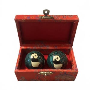 May include: A red box with a hinged lid, containing two dark green decorative balls. Each ball features a panda bear design with black and white accents. The box is lined with red fabric and has a gold-coloured clasp.