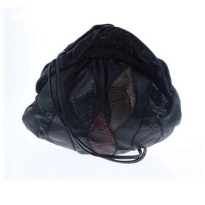 May include: Black leather drawstring bag with a patchwork design. The bag features textured panels in green, blue, brown, and burgundy. The bag has a drawstring closure and a shoulder strap.