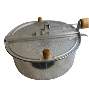 Peut inclure: Un appareil à popcorn vintage avec un corps et un couvercle en métal argenté. Le couvercle présente un motif floral et deux boutons en bois. Une poignée en bois s'étend sur le côté. L'appareil est conçu pour une utilisation sur la cuisinière.