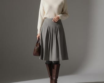 Falda midi plisada de punto gris jaspeado con corte en A y talle alto, estilo clásico de oficina.