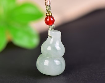 May include: A jade gourd pendant with a green and white hue, suspended by a green cord with a red bead and gold accents. The gourd shape is a traditional symbol of health and longevity.