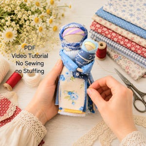 May include: A fabric doll featuring a blue plaid head covering and a floral dress, holding a smaller doll wrapped in blue fabric. The text PDF Video Tutorial No Sewing no Stuffing is visible. Crafting supplies include fabric stacks, thread, and scissors.