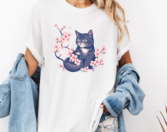 Puede incluir: Camiseta blanca con un gato negro sentado en un árbol de cerezo en flor rosa.