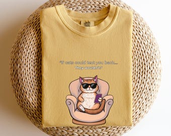 May include: A mustard yellow t-shirt with a cartoon cat wearing sunglasses and holding a phone. The text on the shirt reads "If cats could text you back... They wouldn't."