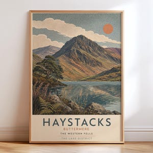 May include: A rectangular wall art print featuring a landscape illustration of Haystacks in Buttermere, The Lake District. The image shows a mountain, a lake, trees, and a sun. Text reads: HAYSTACKS, BUTTERMERE, THE WESTERN FELLS, THE LAKE DISTRICT.