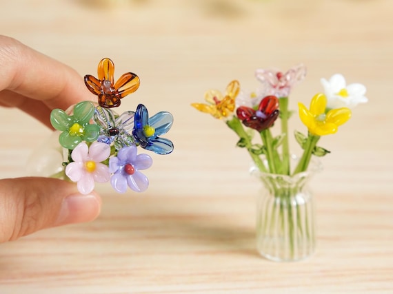 Tiny hand-sculpted glass flower bouquets tied to your birth month — impossibly delicate and the kind of thing you stare at wondering how it was made.