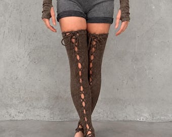 May include: A dark gray sleeveless top and matching shorts paired with brown arm warmers and brown thigh-high leg warmers featuring a vertical lace-up design with crisscross ties running down the front of each leg piece.