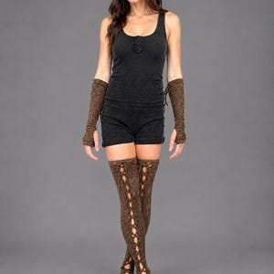 May include: A black sleeveless tank top and matching shorts set paired with brown arm warmers and matching thigh-high leg warmers. The leg warmers feature a vertical lace-up design with crisscross ties running down the front of each leg.