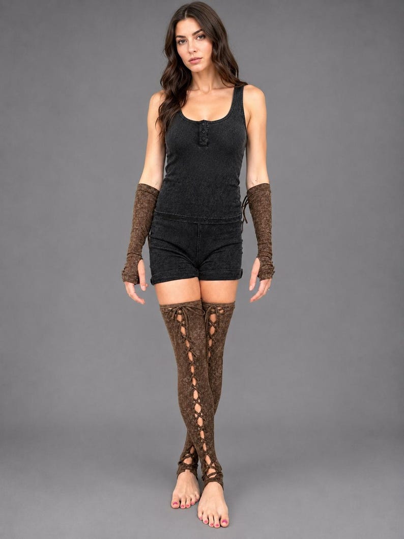 May include: A black sleeveless tank top and matching shorts set paired with brown arm warmers and matching thigh-high leg warmers. The leg warmers feature a vertical lace-up design with crisscross ties running down the front of each leg.
