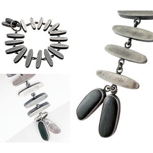 May include: A bracelet composed of multiple elongated, brushed silver-toned metal links connected by small rings. The links feature a textured, matte finish on one side and smooth, dark, solid-colored oval inserts on the reverse side of the chain.